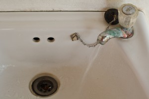 White sink and faucet with green stains.